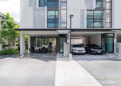 Modern residential building with two cars parked in the driveway and an outdoor seating area