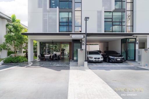 Modern residential building with two cars parked in the driveway and an outdoor seating area