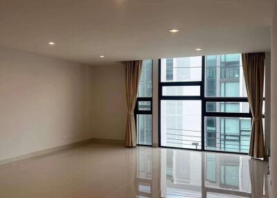 Spacious living room with large windows and tiled floor