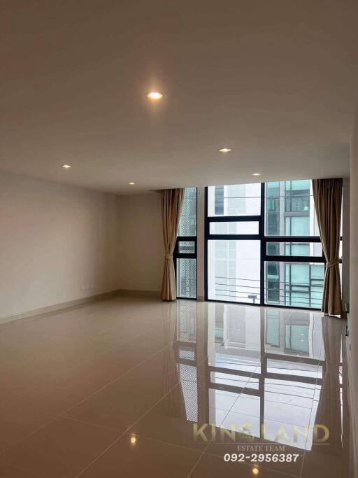 Spacious living room with large windows and tiled floor