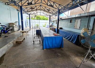 Outdoor seating area in a building with long table, fans, and other facilities