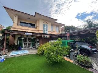 Exterior view of a two-story house with a garden and carport