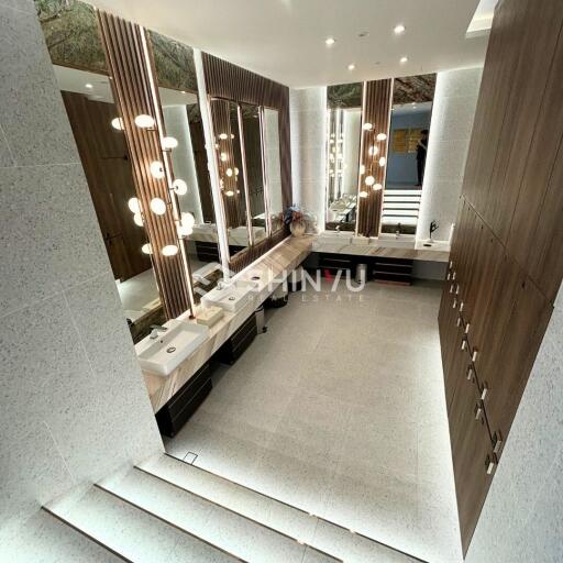 Modern bathroom with illuminated mirrors, dual sinks, and wooden cabinets