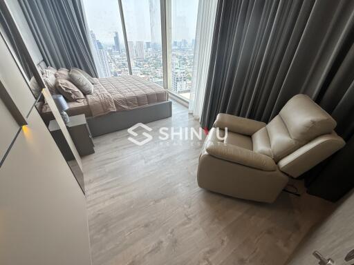 Modern bedroom with city view, bed and recliner