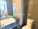 Modern bathroom with sink and toilet, view into bedroom