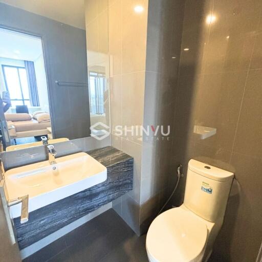 Modern bathroom with sink and toilet, view into bedroom