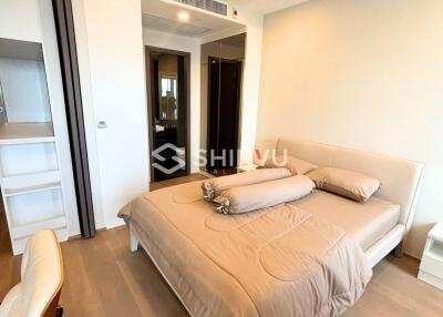 Modern bedroom with beige bedding, wooden flooring, and a built-in wardrobe