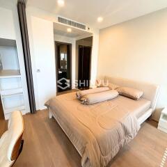 Modern bedroom with beige bedding, wooden flooring, and a built-in wardrobe