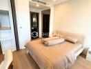 Modern bedroom with beige bedding, wooden flooring, and a built-in wardrobe