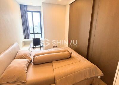 Modern bedroom with a large bed, window with natural light, and a study desk