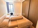 Modern bedroom with a large bed, window with natural light, and a study desk