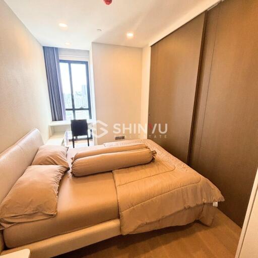 Modern bedroom with a large bed, window with natural light, and a study desk