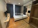 Modern bedroom with wooden flooring, large mirrored wardrobe, and wall-mounted TV.