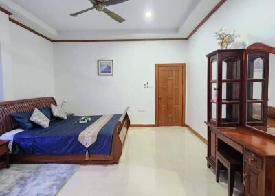 Spacious and well-lit bedroom with ceiling fan and wooden furniture