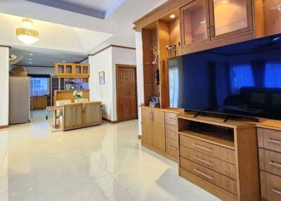 Spacious living room with built-in wooden entertainment center and kitchen view