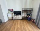 Living room with wooden flooring, TV stand, and shelving unit