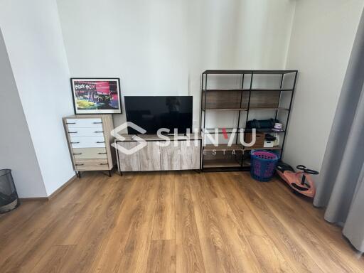 Living room with wooden flooring, TV stand, and shelving unit