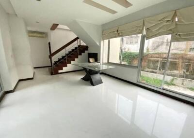 Modern living room with large windows, neutral colors, and a staircase