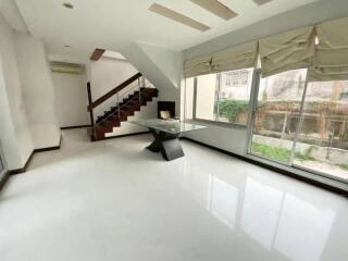 Modern living room with large windows, neutral colors, and a staircase