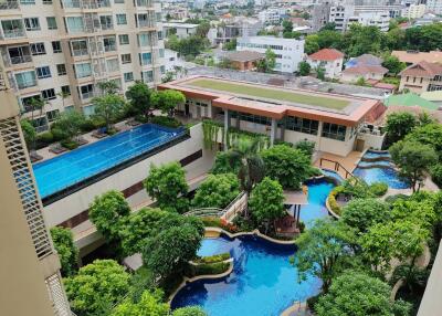 View of residential building with swimming pools and lush greenery