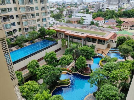 View of residential building with swimming pools and lush greenery