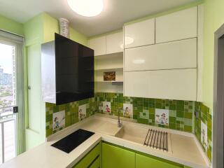 Modern kitchen with green and white cabinetry and tile backsplash