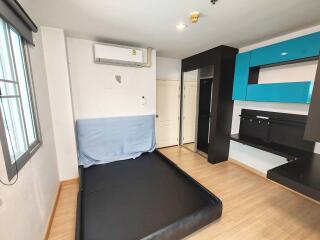 Modern bedroom with light wood flooring, black bed frame, air conditioner, and built-in shelves.