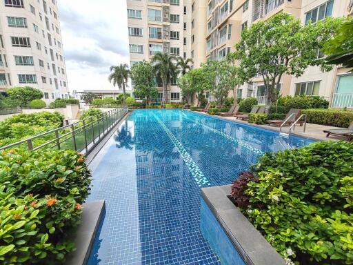 Swimming pool surrounded by lush greenery and apartment buildings