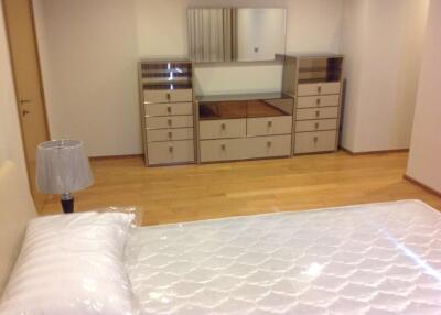 A bedroom with a bed, wooden floor, and a dresser with a mirror