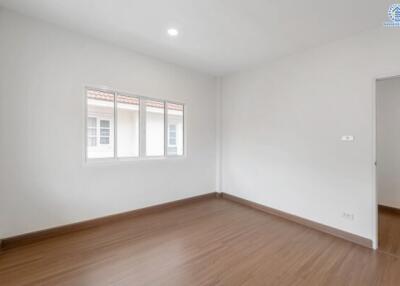 Spacious empty bedroom with wooden floor and large window