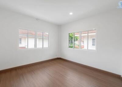 Bright empty bedroom with large windows and wooden floors