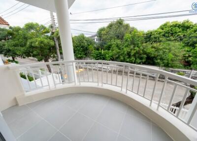 Spacious curved balcony with railing and a view of greenery and streets