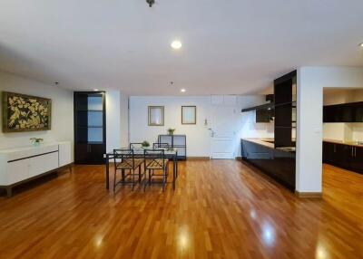 Spacious living area with wooden flooring, dining table, and modern kitchen