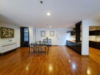 Spacious living area with wooden flooring, dining table, and modern kitchen