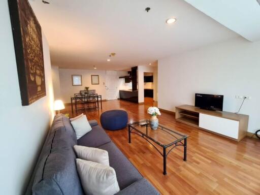 Spacious and modern living room with hardwood flooring, cozy seating area, and wall-mounted TV