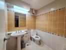 Modern bathroom with orange and white tiles, a white sink, and a toilet