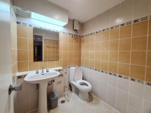 Modern bathroom with orange and white tiles, a white sink, and a toilet