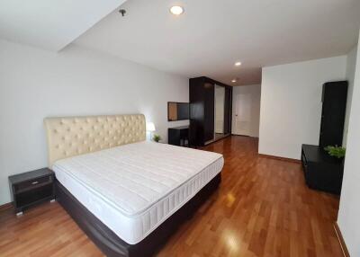 Spacious bedroom with wooden flooring and ample lighting