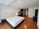 Spacious bedroom with wooden flooring and ample lighting