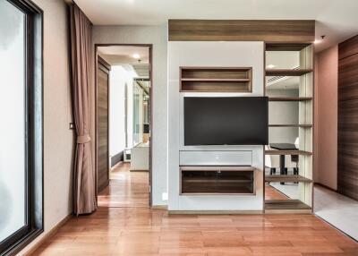 Modern living room with wooden flooring, TV, and built-in shelves