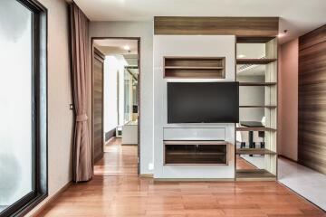 Modern living room with wooden flooring, TV, and built-in shelves