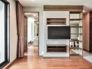 Modern living room with wooden flooring, TV, and built-in shelves