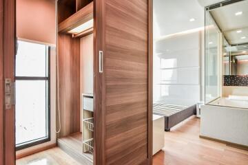 Modern bedroom with built-in wooden wardrobe and glass-enclosed bathroom