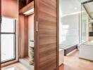 Modern bedroom with built-in wooden wardrobe and glass-enclosed bathroom