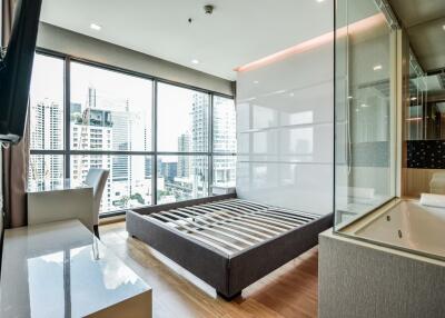 Modern bedroom with large windows, city view, and open bathroom