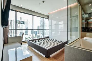 Modern bedroom with large windows, city view, and open bathroom