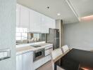 Modern kitchen and dining area with sleek white cabinets and contemporary appliances