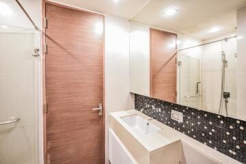 Modern bathroom with wooden door and tiled wall