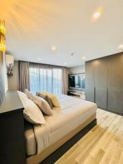 Modern bedroom with large bed, TV area, and wardrobe