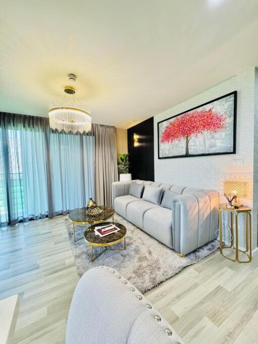 Contemporary living room with large gray sofa, chandelier, and modern decor